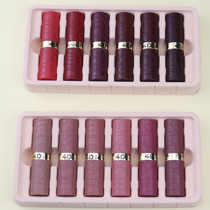 Set of red and burgundy lipsticks in two pink cases on a light beige background.