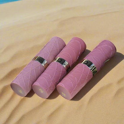 Pink cylindrical products with gold accents on a white surface with pink flowers and green leaves.